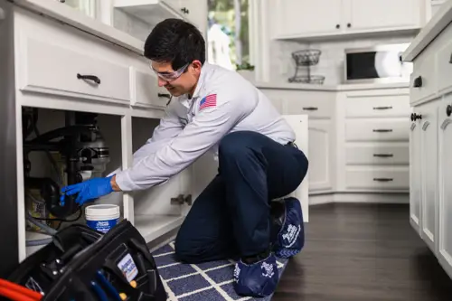 Benjamin Franklin Plumbing Tech, Diego, working under a sink in a home in Lakeland, FL