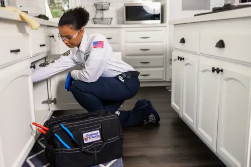 Benjamin Franklin Plumbing Tech, Layla, working on fixing pipes under a kitchen sink in Lakeland, FL